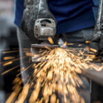 Industrial worker cutting metal with many sharp sparks